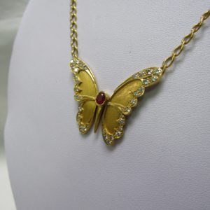 Cadena con colgante integrado, en Oro de 18k. en forma de Mariposa, con Rubí central de 0,60 ct. y 38 Diamantes talla Brillante de 1,10 ct. (I-J/SI1). 13,60 gr.