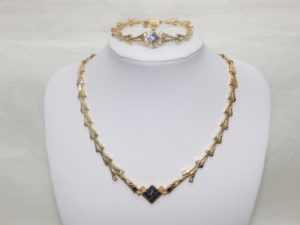 Conjunto de Collar y Brazalete en Oro, con eslabones en V, y rombo central cuajado de "blue strass" y circonitas.