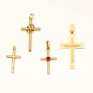 Lote de cuatro crucifijos para colgar en oro de 18k. España. Siglo XX.