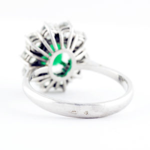 Sortija de oro blanco con esmeralda central y orla de diamantes.