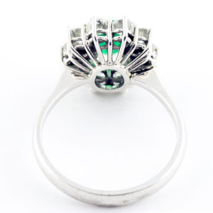 Sortija de oro blanco con esmeralda central y orla de diamantes.