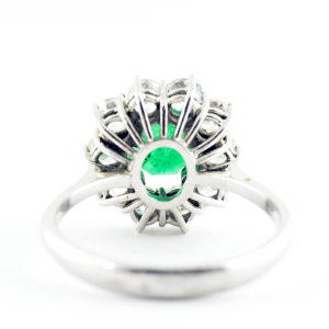 Sortija de oro blanco con esmeralda central y orla de diamantes.