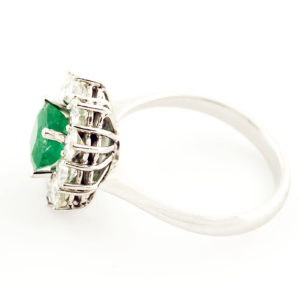 Sortija de oro blanco con esmeralda central y orla de diamantes.