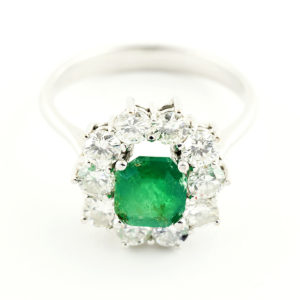 Sortija de oro blanco con esmeralda central y orla de diamantes.