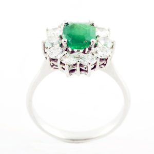 Sortija de oro blanco con esmeralda central y orla de diamantes.
