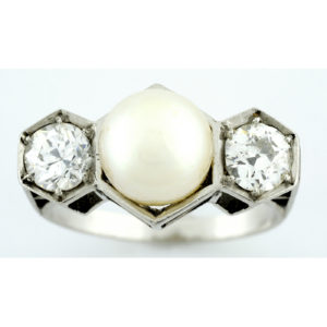 Sortija en Oro Blanco, con Perla Sedosa Central y Dos Diamantes Talla Antigua Europea de 0,55 ct. (H-I/SI1) y 0,46 ct. (J-K/SI1). Certificado IGE.