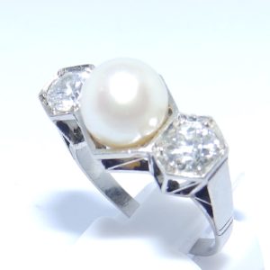 Sortija en Oro Blanco, con Perla Sedosa Central y Dos Diamantes Talla Antigua Europea de 0,55 ct. (H-I/SI1) y 0,46 ct. (J-K/SI1). Certificado IGE.