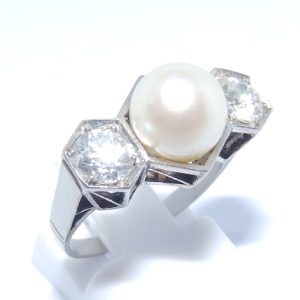 Sortija en Oro Blanco, con Perla Sedosa Central y Dos Diamantes Talla Antigua Europea de 0,55 ct. (H-I/SI1) y 0,46 ct. (J-K/SI1). Certificado IGE.