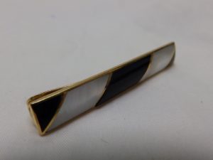 Pisacorbata en Oro de 18k con incrustaciones de nácar y esmalte negro. Peso: 11,10 gr.