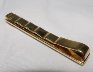 Pisacorbata en Oro de 18k con incrustaciones de nácar y esmalte negro. Peso: 11,10 gr.