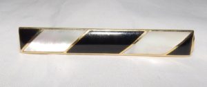 Pisacorbata en Oro de 18k con incrustaciones de nácar y esmalte negro. Peso: 11,10 gr.