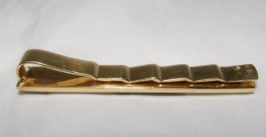 Pisacorbata en Oro de 18k con incrustaciones de nácar y esmalte negro. Peso: 11,10 gr.