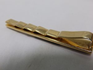 Pisacorbata en Oro de 18k con incrustaciones de nácar y esmalte negro. Peso: 11,10 gr.