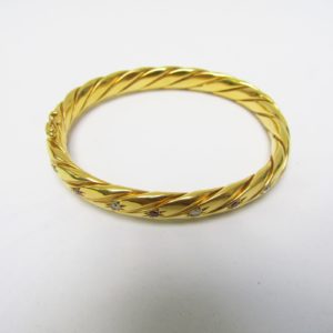 Pulsera Rígida y Oval, sogueada, en Oro de 18k con 5 Diamantes y 4 Rubíes, talla Brillante, de 0,50 ct. y 0,40 ct. respectivamente. Peso: 28 gr.