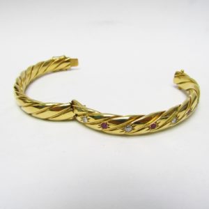 Pulsera Rígida y Oval, sogueada, en Oro de 18k con 5 Diamantes y 4 Rubíes, talla Brillante, de 0,50 ct. y 0,40 ct. respectivamente. Peso: 28 gr.