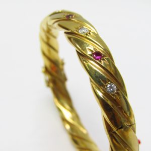 Pulsera Rígida y Oval, sogueada, en Oro de 18k con 5 Diamantes y 4 Rubíes, talla Brillante, de 0,50 ct. y 0,40 ct. respectivamente. Peso: 28 gr.