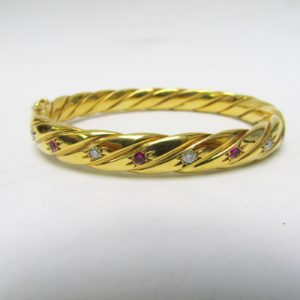 Pulsera Rígida y Oval, sogueada, en Oro de 18k con 5 Diamantes y 4 Rubíes, talla Brillante, de 0,50 ct. y 0,40 ct. respectivamente. Peso: 28 gr.