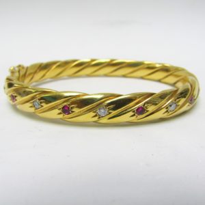 Pulsera Rígida y Oval, sogueada, en Oro de 18k con 5 Diamantes y 4 Rubíes, talla Brillante, de 0,50 ct. y 0,40 ct. respectivamente. Peso: 28 gr.