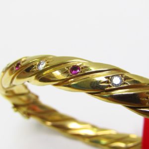 Pulsera Rígida y Oval, sogueada, en Oro de 18k con 5 Diamantes y 4 Rubíes, talla Brillante, de 0,50 ct. y 0,40 ct. respectivamente. Peso: 28 gr.