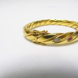 Pulsera Rígida y Oval, sogueada, en Oro de 18k con 5 Diamantes y 4 Rubíes, talla Brillante, de 0,50 ct. y 0,40 ct. respectivamente. Peso: 28 gr.