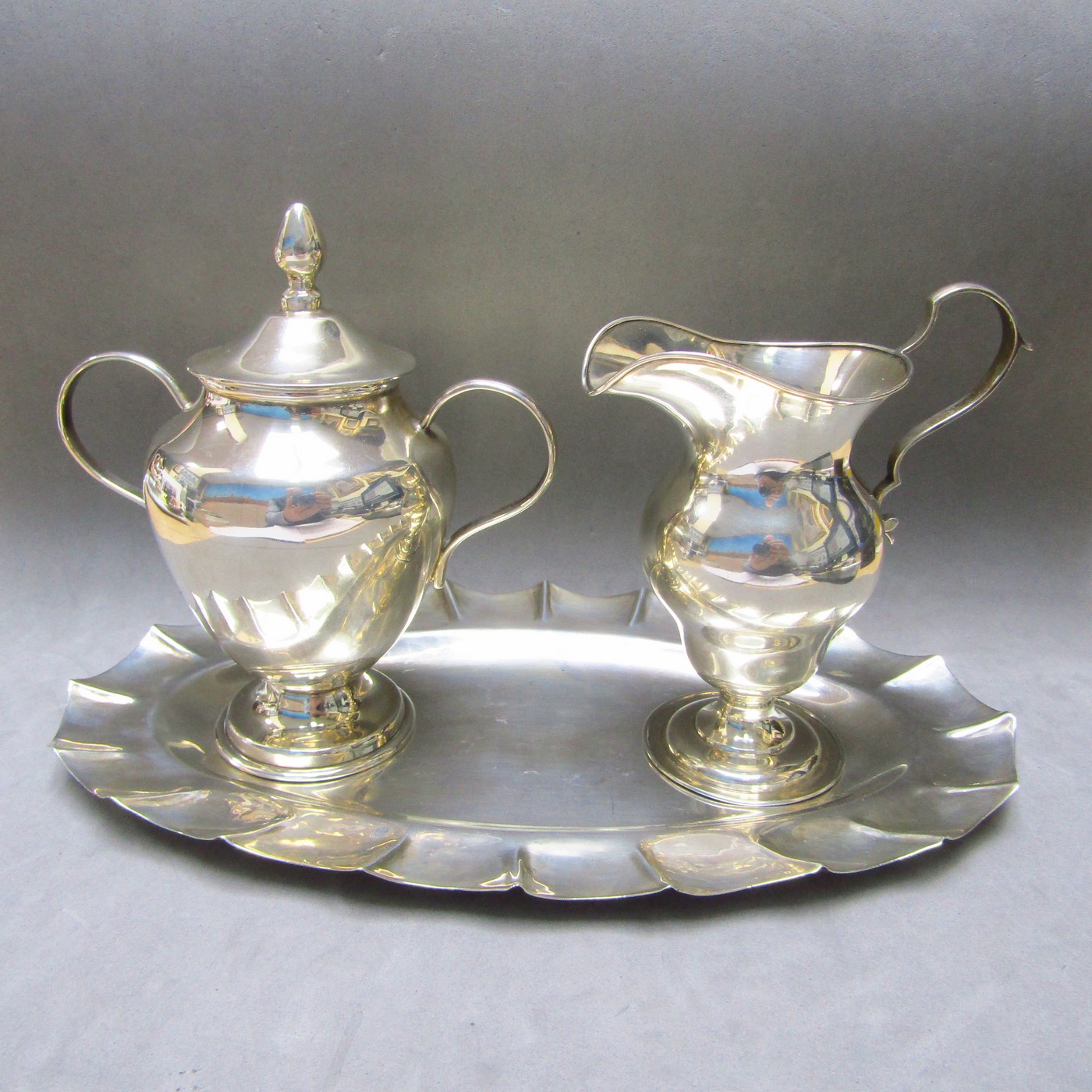 Conjunto formado por bandeja y azucarero en plata de Ley mexicana y Lechera en Plata Inglesa. Londres, 1910. Conjunto formado por bandeja y azucarero en plata de Ley mexicana y Lechera en Plata Inglesa. Londres, 1910.