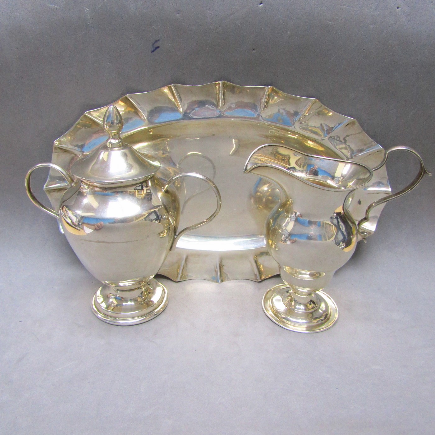 Conjunto formado por bandeja y azucarero en plata de Ley mexicana y Lechera en Plata Inglesa. Londres, 1910. Conjunto formado por bandeja y azucarero en plata de Ley mexicana y Lechera en Plata Inglesa. Londres, 1910.