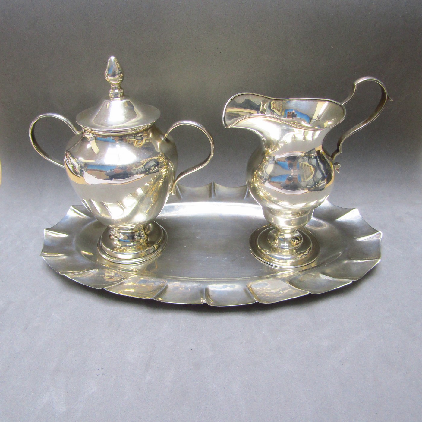 Conjunto formado por bandeja y azucarero en plata de Ley mexicana y Lechera en Plata Inglesa. Londres, 1910. Conjunto formado por bandeja y azucarero en plata de Ley mexicana y Lechera en Plata Inglesa. Londres, 1910.